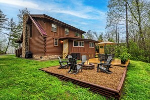 Une cabane en rondins dotée d’une terrasse, d’un espace salon extérieur et d’un foyer.