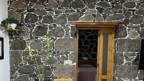 Zona pranzo con parete in pietra, tavolo e sedie di legno.