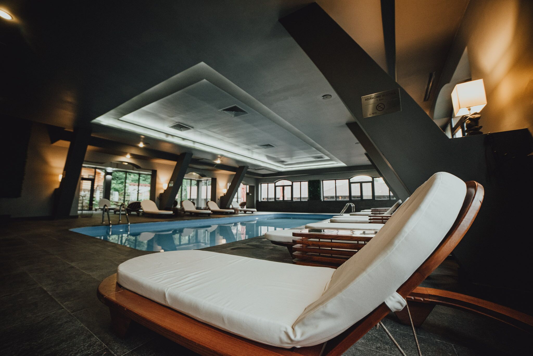 Un espace piscine intérieur moderne, doté de chaises longues et de transats.