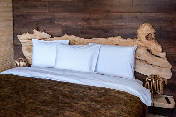 A bed with white bedding, a wooden headboard, and two bedside tables with woven baskets.