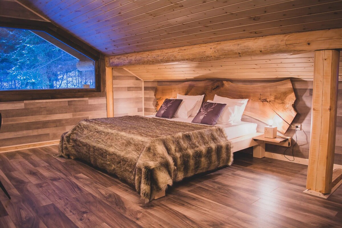 A cozy bedroom with a wooden headboard, a bed with a fur throw, and a nightstand with a lamp.