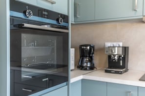 Enjoy cooking and brewing in this well-equipped kitchen with a digital oven, microwave, coffee maker, and espresso machine.
