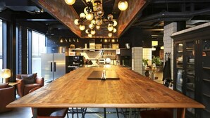 A spacious kitchen with a long wooden table, modern appliances, and a unique ceiling light fixture. - JOIVY at VITA Fountainbridge - Adults only (Edinburgh)
