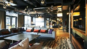 A modern lounge area with a large sofa set, a coffee table, and a patterned rug. - JOIVY at VITA Fountainbridge - Adults only (Edinburgh)