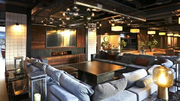 A modern lounge area with a large sofa set, a coffee table, and a flat-screen TV mounted on the wall. - JOIVY at VITA Fountainbridge - Adults only (Edinburgh)