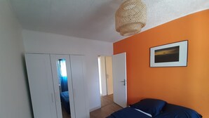 Une chambre à coucher avec un lit, une armoire et un luminaire suspendu.