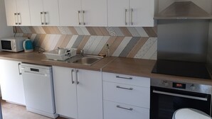Une cuisine moderne avec des meubles blancs, un four à micro-ondes, un grille-pain, un évier et un four.