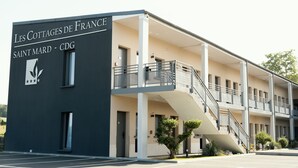 A multi-story building with a sign reading "Les Cottages de France Saint Mard - CDG".