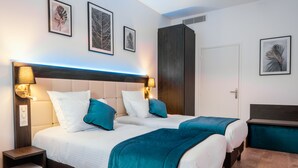 A double bed with teal bedding, two bedside lamps, and a nightstand.