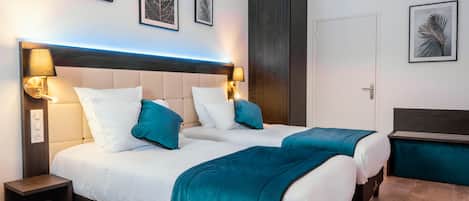 Una cama doble con ropa de cama color turquesa, dos lámparas de noche y una mesita de noche.