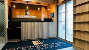 A reception area with a wooden counter, a logo, and a blue carpet with text.