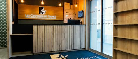 A reception area with a wooden counter, a logo, and a blue carpet with text.