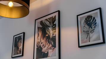 Drei gerahmte Pflanzenbilder an einer Wand, eine Pendelleuchte und ein Teilansicht der Decke.