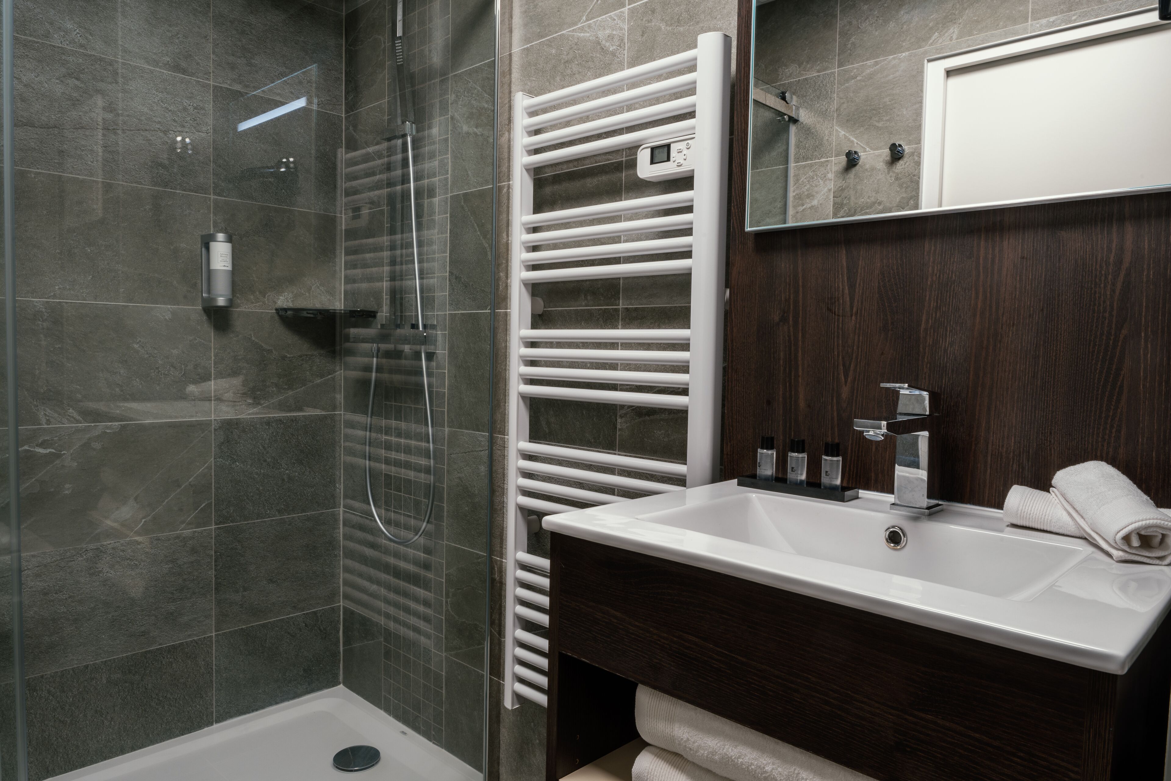 A modern bathroom with a glass shower enclosure, a built-in white sink, and a dark wood vanity.