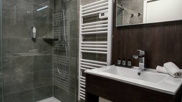 A modern bathroom with a glass shower enclosure, a built-in white sink, and a dark wood vanity.