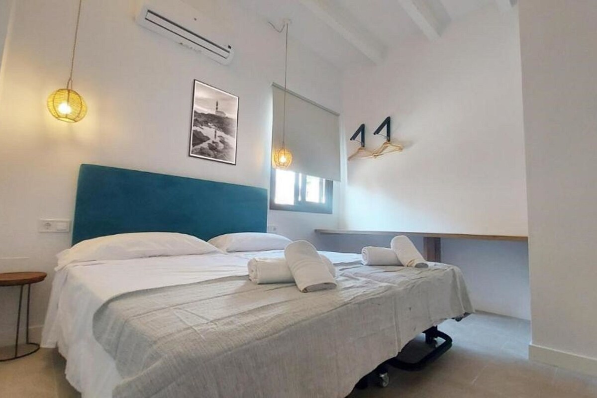 Un dormitorio moderno con una cama grande, una mesita auxiliar pequeña, un aire acondicionado instalado en la pared y un cuadro enmarcado.