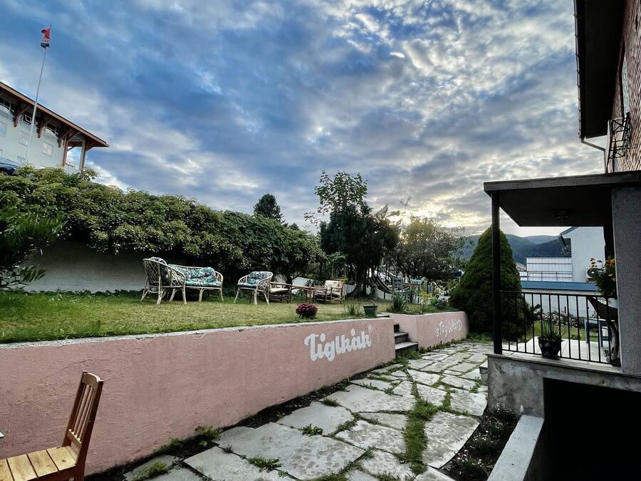 Un patio con un sendero de piedra, mobiliario exterior y una pared con el nombre 'Tiglouk'.