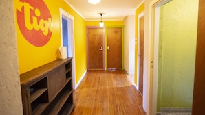 A hallway with wooden flooring, a wooden bench, and a wall with a large 'Tig' sign. - Tiglkåk - Hostel (Rauma)