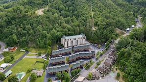 Suuri hotelli, jossa on useita rakennuksia, ja se sijaitsee tiheän metsän ja mäkisen maiseman ympäröimänä.