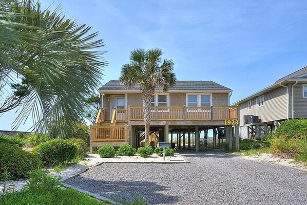 A two-story building with a wooden deck and a covered entrance. - Experience oceanfront bliss at 'A Painted Palm Tree' in Oak Island, NC – ideal for 9 guests. (Oak Island)