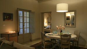 Uma sala de jantar com mesa redonda, cadeiras, velas e um candelabro.