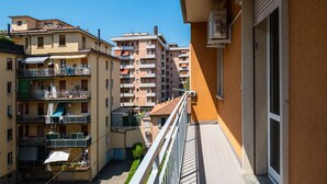Un immeuble résidentiel à plusieurs étages, doté de balcons, d’un petit espace jardin et offrant une vue sur un ciel dégagé.