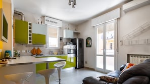 Eine moderne Küche mit grünen Schränken, einem Kühlschrank und einem Essbereich mit einem weißen Tisch und zwei Barhocker.