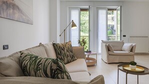 Un salon moderne avec un canapé, des fauteuils, une petite table et un radiateur.