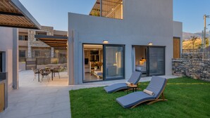 Een modern huis met een terras, zitplaatsen buiten en uitzicht op het omliggende landschap.