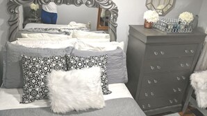 Un dormitorio con una cama grande, un aparador y un espejo en la pared.