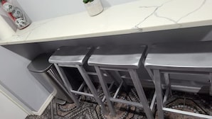Una zona de bar con tres taburetes y una encimera de mármol.