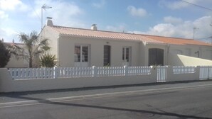 Un bâtiment d’un seul étage, doté d’un toit recouvert de tuiles, de murs extérieurs blancs et d’une clôture blanche.