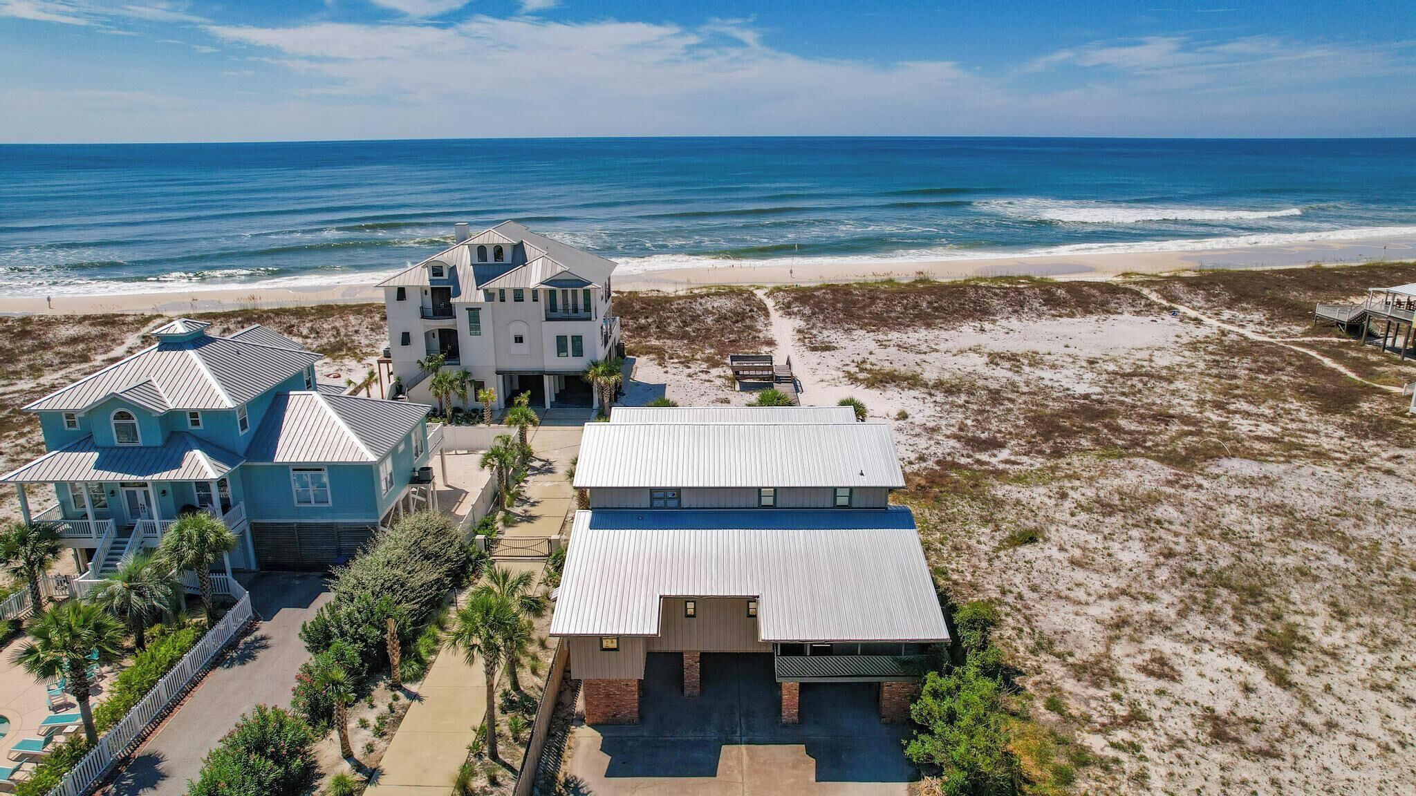 A beachfront property with multiple buildings, including a large house with a balcony overlooking the ocean.