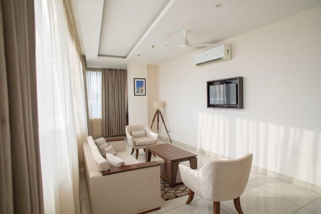 Una sala de estar moderna con un sofá, sillones, una mesa de centro y una lámpara de trípode.