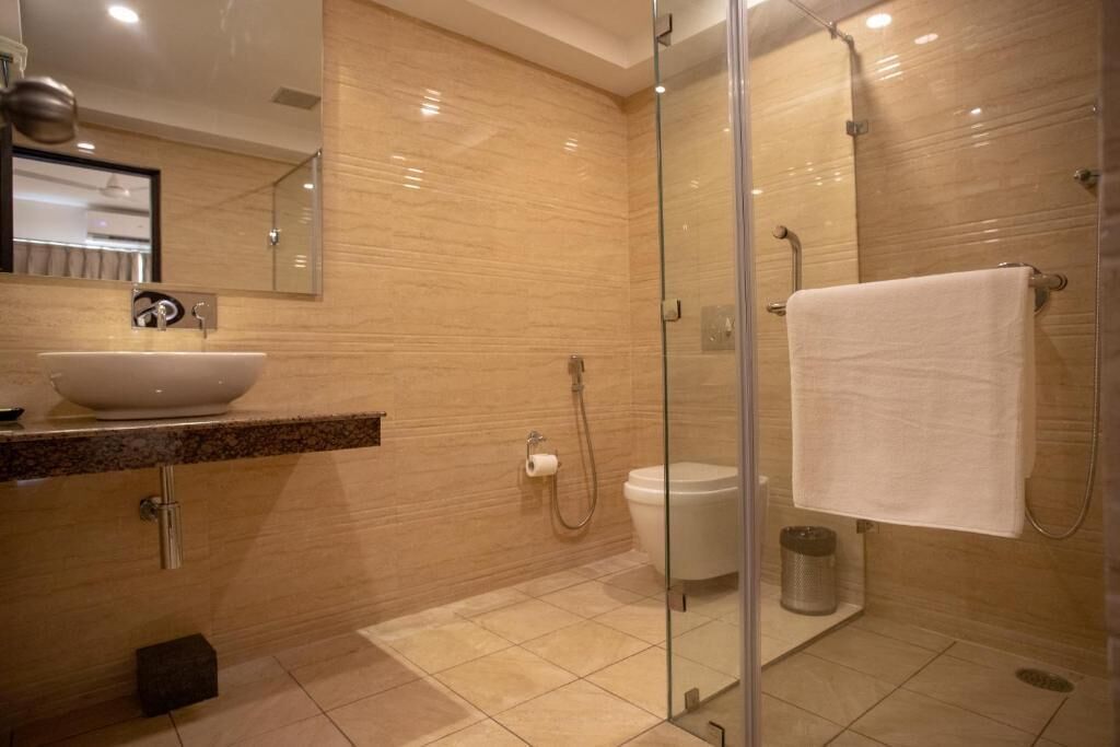 Een moderne badkamer met een douchecabine van glas, een witte wastafel en een grote spiegel.