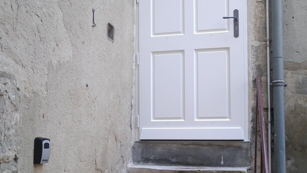 A white door with a small window above it, leading to a set of stone steps. - Charming apartment ideally located (Bayeux)