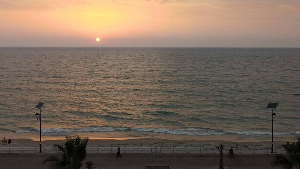A sunset over the ocean with a beach in the foreground.