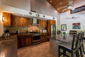 A modern kitchen with wooden cabinets, a stainless steel refrigerator, a microwave, and a gas stove.