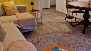 Ein Wohnzimmer mit einer Couch, einem kleinen Tisch und einem Essbereich mit Tisch und Stühlen.