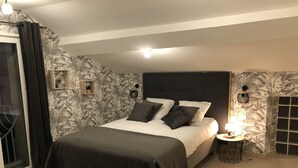 Un dormitorio con cama, mesita de noche, lámpara y ventana con cortinas.