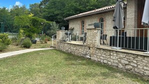 Un edificio de piedra con techo de tejas, mobiliario exterior y un patio amurallado.