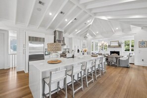 A spacious kitchen with a central island, modern appliances, and a high ceiling with exposed beams. - EXQUISITE LUXURY HOME w/ POOL, LSV, BIKES! NEXT TO CAMP WATERCOLOR! Pet Friendly! (Santa Rosa Beach)