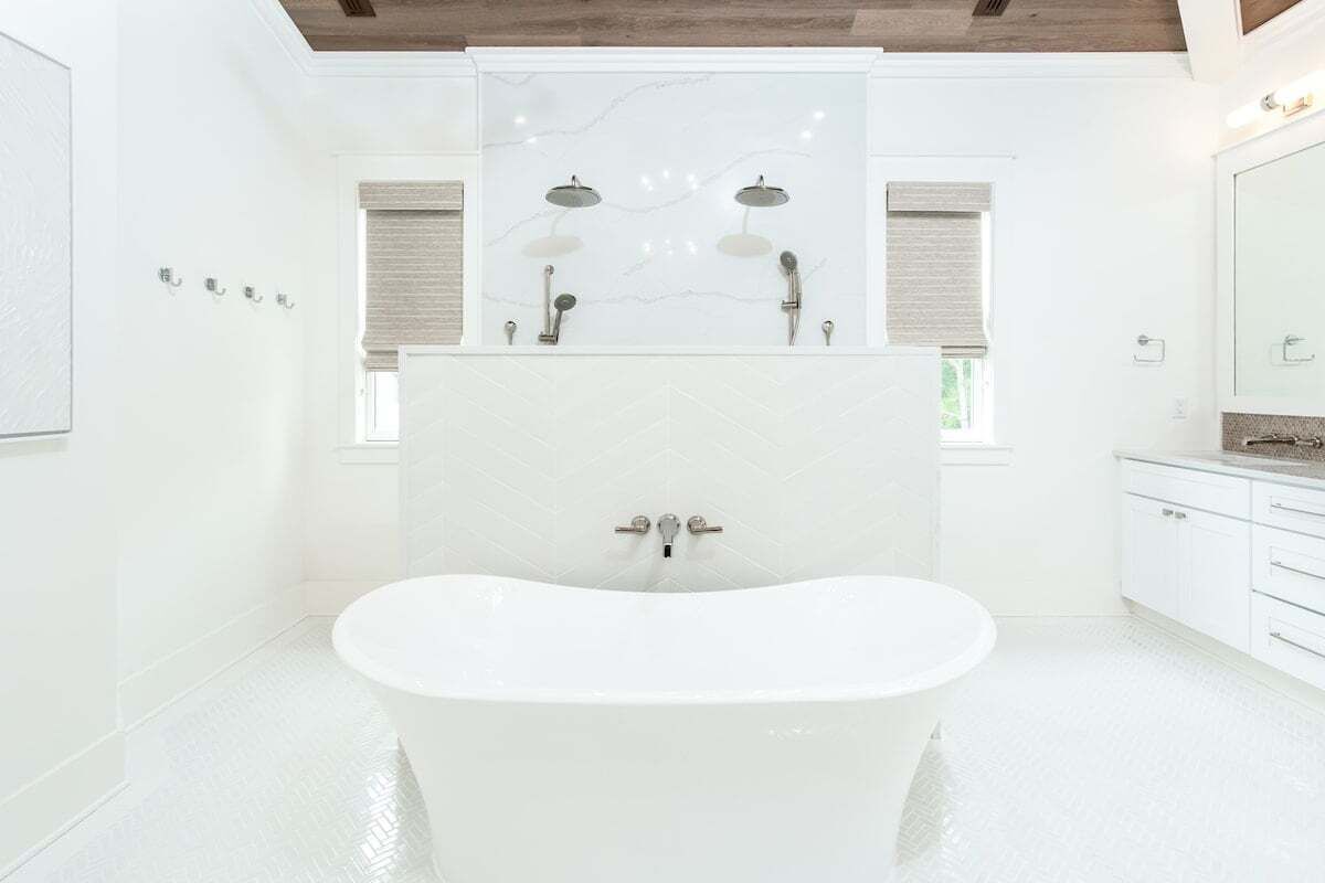 Une salle de bain moderne avec une baignoire sur pieds, un grand miroir et un meuble-lavabo doté d’un plan de travail.