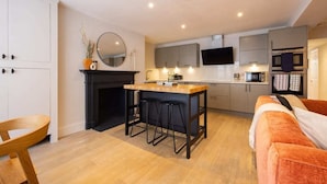 Een compacte keuken met een centraal eiland, een flatscreen televisie boven de werkruimte en een magnetron boven de oven.