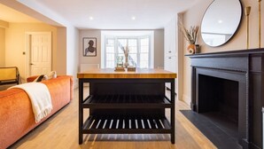 Een moderne woonkamer met een bank, een houten salontafel, een open haard en een grote spiegel.