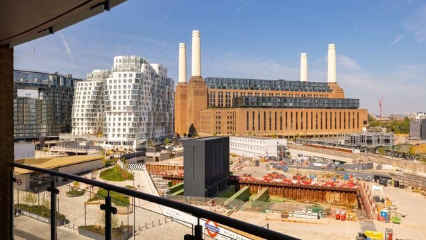 A view of a modern building with multiple chimneys, a glass facade, and a construction site in the foreground. - The Nine Elms Lane Arms - Stunning & Bright 2bdr Flat With Balconies (London)