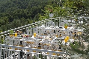 Enjoy meals with a scenic view from this outdoor dining area, featuring a beautifully set table with comfortable seating.