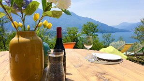 Une table ornée d’un vase de fleurs, d’une bouteille et d’un verre, le tout placé devant un paysage montagneux pittoresque.