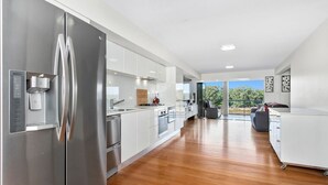 Une cuisine moderne dotée d’appareils électroménagers en acier inoxydable, de meubles blancs et d’un grand îlot central.