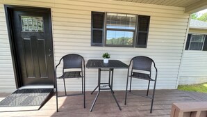 Eine Veranda mit zwei Stühlen, einem kleinen Tisch und einer Tür mit Fenster.